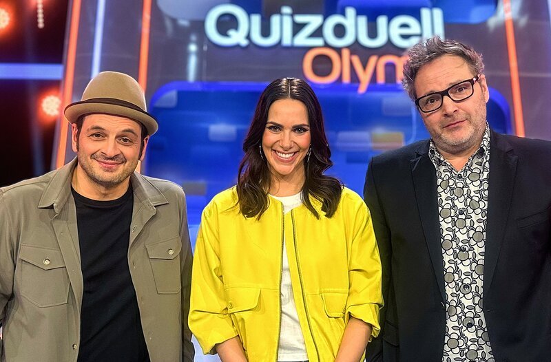 Moderatorin Esther Sedlaczek (M.) mit den Kandidaten des Teams „Comedy“: Kaya Yanar (l.) und Paul Panzer (r.) – Bild: ARD/​ITV Studios