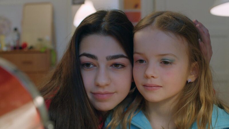 Wie eine große Schwester hat Adriana (Esra Nur Kula) Sigrid (Maria Ross) geholfen, sich zu schminken. Nun betrachten sie das Ergebnis im Spiegel. – Bild: WDR/​NRK /​ KiKA