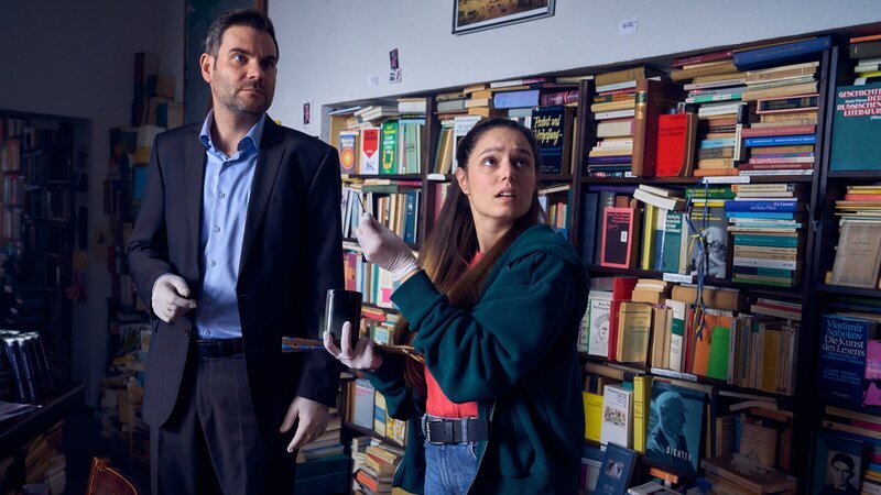 Die Ermittler Jonas Fischer (Lukas Piloty) und Amira Mahdi (Aylin Ravanyar) sehen sich im Antiquariat des Opfers um. Alles sieht danach aus, als würde der Mord mit einem alten Buch im Zusammenhang stehen, das das Opfer in seinem Keller gefunden hatte. Doch wo ist das Buch abgeblieben? – Bild: ZDF