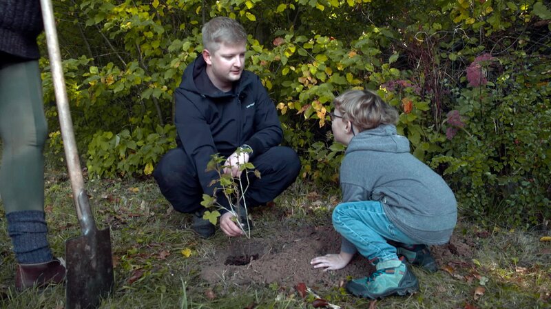 Reporter Simon Rustler pflanzt mit Yaron Scheidler (li.) einen Beerenstrauch. – Bild: HR