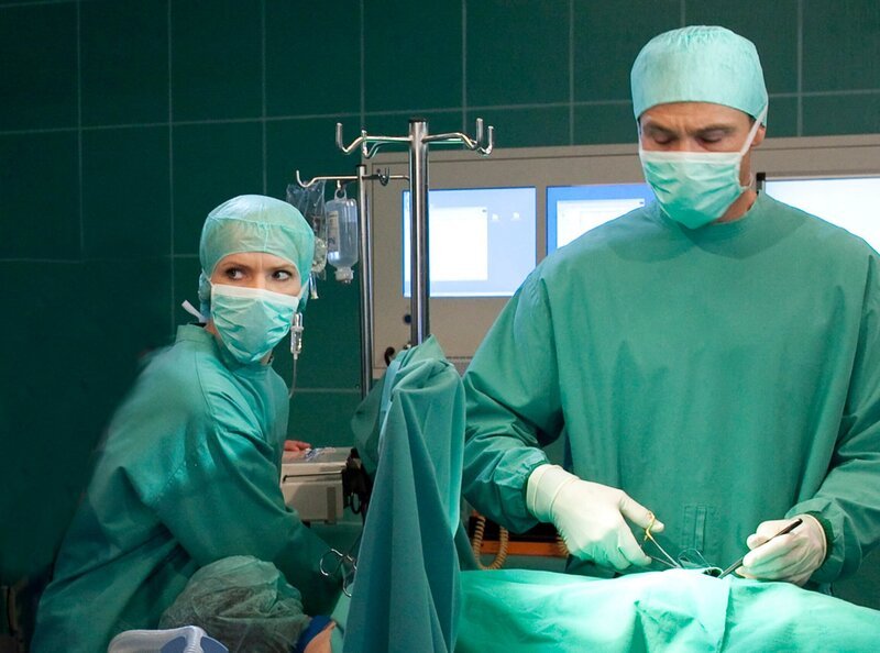 Bei der Operation von Georg Büttner (Staphan Schad, liegend) kommt es zur Verblüffung von Dr. Kathrin Globisch (Andrea Kathrin Loewig) und Dr. Martin Stein (Bernhard Bettermann, rechts) zur gleichen Narkosemittelunverträglichkeit, wie bei der OP von Stefan Merck. Da diese maligne Hyperthermie äußerst selten ist, suchen die Ärzte nach Verbindungen zwischen den beiden Patienten und kommen zu einem verblüffenden Ergebnis. – Bild: MDR/​MDR/​Krajewsky