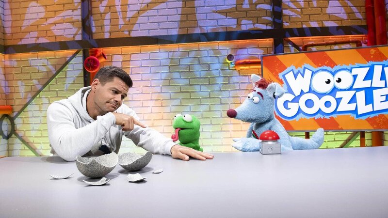 Woozle (re.) hat das Ei einer kuscheligen Woozlinger Flausch-Echse mit ins Studio gebracht, aber Simón (li.) ist skeptisch. Und tatsächlich: Woozle brütet stattdessen aus Versehen ein beängstigendes Chawoozleon (mi.) aus, das gleich darauf auch noch verschwindet! Ob die beiden es einfangen können, bevor es das ganze Studio verwüstet? – Bild: Annette Etges/​SUPER RTL