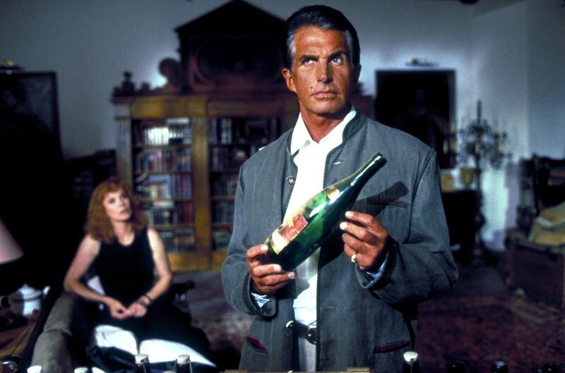 Simone Grohe (Stefanie Powers, l.), die Verlobte des wohlhabenden Klinikchefs Peter Donner, hat eine Affäre mit dessen Vermögensberater Karl von Ostenberg (George Hamilton, r.) – Bild: Columbia Pictures