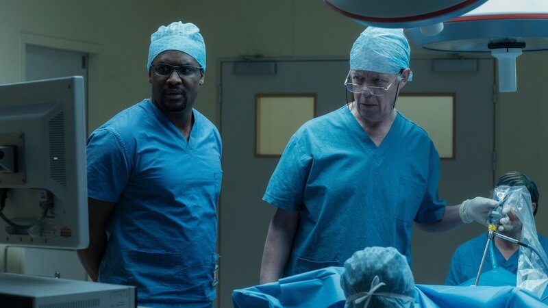 Als der Oberarzt Mr. Lockhart (Alex Jennings, r.) erfährt, dass eine Patientin entgegen seiner Anweisung operiert wird, sind er und sein Assistent Julian (Kadiff Kirwan, l.) bereit, die Aktion zu beenden. Doch dann machen die beiden eine Entdeckung, die alles verändert. – Bild: Anika Molnar /​ ZDF