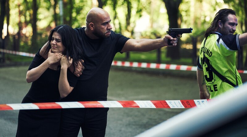 Stulle (Frederick Lau, re.) und Barro (Veysel Gelin, Mitte) nutzen die Geisel Vanessa (Ruby O. Fee) als Schutzschild. – Bild: ARD Degeto/​Marco Fischer