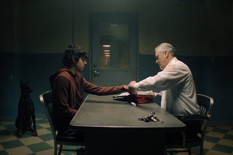 Chief Dandridge (Bruce Campbell, r.) nimmt sich Dylan (Emjay Anthony, l.) auf dem Polizeirevier vor. Was weiß Dylan über den verschwundenen Teenager Ryan und hat seine Heavy-Metall-Band etwas mit dem mysteriösen Vorfall zu tun? – Bild: ZDF und PEACOCK