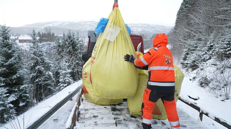 Ole Henrik steht auf der Pritsche und manövriert die 1-Tonnen-Säcke mit Streusalz, während der Kran sie aus dem verunglückten Anhänger hebt. – Bild: National Geographic