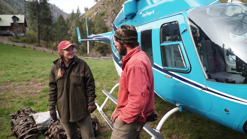 Aubrey Barton (l.) and boyfriend, Pete Metz (r.) in front of the helicopter that will help deliver supplies to Indian Creek (slightly different angle). – Bild: Discovery Channel /​ Discovery Communications, LLC