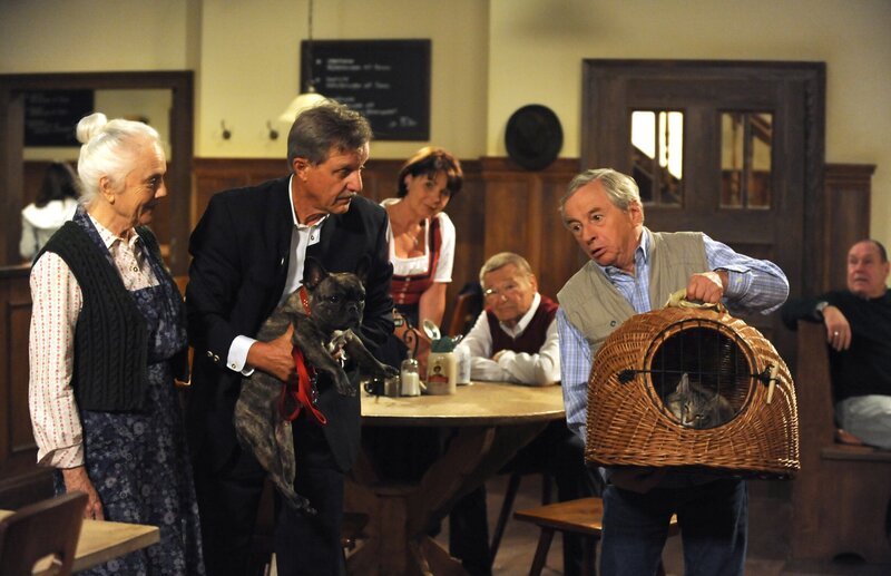 Im Brunnerwirt geraten Hundebesitzer Schattenhofer und Katzenbesitzer Gerstl aneinander. Von links: Theresa Brunner (Ursula Erber), Bürgermeister Schattenhofer (Werner Rom) und Gerstl (Gerd Lohmeyer). – Bild: BR/​Marco Orlando Pichler