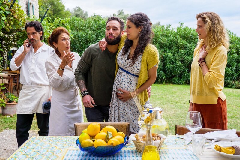 Nell will am Gardasee ihren Fluglehrerinnenschein machen. Davon will sie sich nicht ablenken lassen – weder von ihrem Fluglehrer Lukas (Joshua Grothe) noch von Simone und seiner Familie. Gar nicht so einfach – Rosas Wehen haben gerade eingesetzt. Von links: Simone (Stefano Bernardin), Giovanna (Daniela Ziegler), Diego (Sascha Pederiva) mit Rosa (Liane Forestieri) und Nell (Pia Micaela Barucki). – Bild: ORF/​ZDF/​Florian Licht