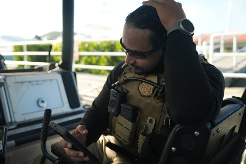 Ein CBP-Agent schaut auf einem Wasserfahrzeug in Mayaguez, P.R., auf sein Telefon. – Bild: National Geographic /​ Lucky 8 TV/​Paul Taggart