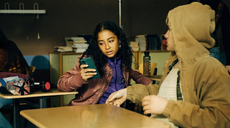 Nola (Samirah Breuer) versucht den Entsperrcode von Corvins (Florian Geißelmann) Handy herauszufinden. – Bild: ARD Degeto Film/​HR/​funk/​Dreamtool Entertainment GmbH/​Elliott Kreyenberg