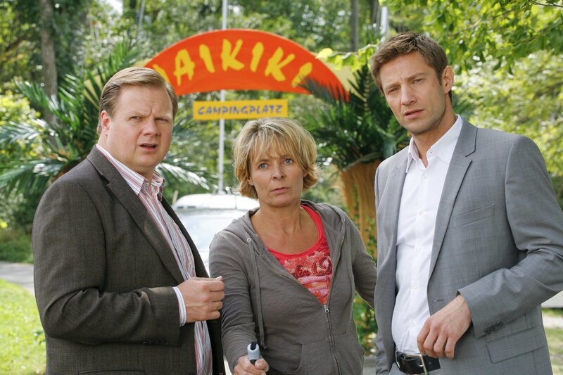 Die Rosenheimer Kommissare Hansen (Igor Jeftic, r.) und Hartl (Michael A. Grimm, l.) verdächtigen Dauercamperin Cornelia Meierling (Susanne Czepl, M.), die eine Affäre mit dem Opfer hatte. – Bild: ZDF/​Christian A. Rieger
