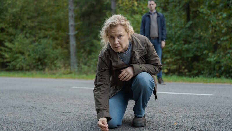 Polizistin Hannah (Eva Melander, l.) entdeckt auf einer Straße am Wald Spuren, die auf einen Unfall hindeuten. Sie informiert ihren Vorgesetzten Gordon (Hannes Fohlin, r.) darüber. – Bild: ZDF und andrej vasilenko