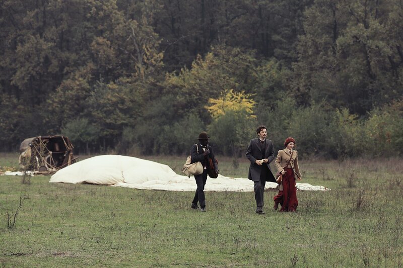 Nach erfolgreicher Alpenüberquerung haben Phileas Fogg (David Tennant, M.), Abigail Fix (Leonie Benesch, r.) und Passepartout (Ibrahim Koma, l.) mit ihrem Heißluftballon eine Bruchlandung auf einer Wiese in Italien hingelegt. – Bild: ZDF und Tudor Cucu