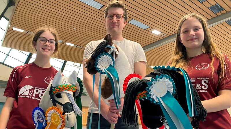 Rebecca (l) und Melina (r) sind begeisterte Hobby Horse-Reiterinnen und zeigen Robert, worauf es bei der Trendsportart ankommt. – Bild: WDR/​tvision