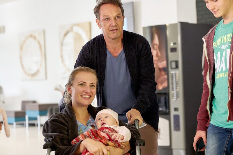 Minas Ex-Mann Reinhard (Max Gertsch) ist mit dessen neuer Frau Leo (Ania Niedieck) und deren neugeborenem Baby ausgerechnet in dem Krankenhaus, in dem Minas Kollege Thaoms Waldeck um sein Leben kämpft, nachdem er angeschossen wurde. r.: Lukas Bäumer (Nico Ramon Kleemann), der gemeinsame Sohn von Mina und Reinhard. – Bild: TVNOW /​ Frank Dicks