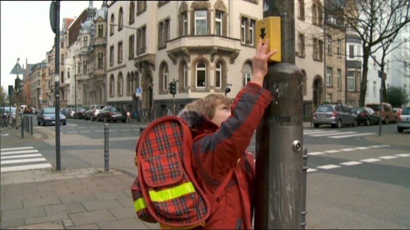 Ein Junge zeigt, wie man sicher die Straße überquert. – Bild: WDR/​Die Sendung mit dem Elefanten