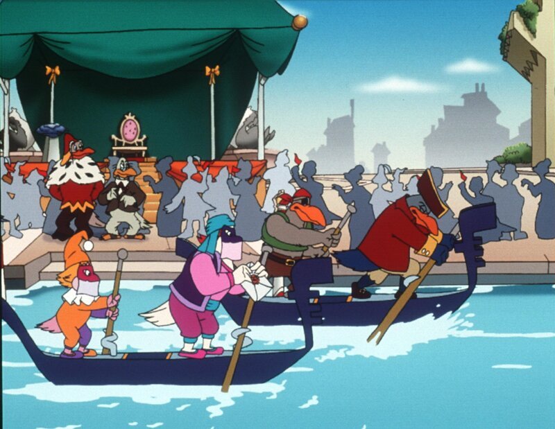 „Die Jagd nach dem Kju Wang“, „Die große Regatta.“ Die gesamte geflügelte Welt von Venedig fiebert der großen Karnevalsregatta entgegen. Drei Teilnehmer-Paare sollen in die Endausscheidung gehen. Marco und Berto, die Bum-Bum-Zwillinge und die zwei geheimnisvollen Piraten qualifizieren sich. Da das Rennen in Karnevalskostümen abgehalten wird, ist es für Yagor ein Leichtes, sich zusammen mit dem Rattenkönig auf einen hinterhältigen Plan zu konzentrieren. Der Sieger des Rennens soll den Kju Wang eigenhändig auf die Turmspitze fliegen. Yagor, der unbedingt siegen will, hat keinesfalls vor, den Kju Wang auf die Turmspitze zu setzen. Er sieht seine Chance kommen. – Bild: ORF/​EBU