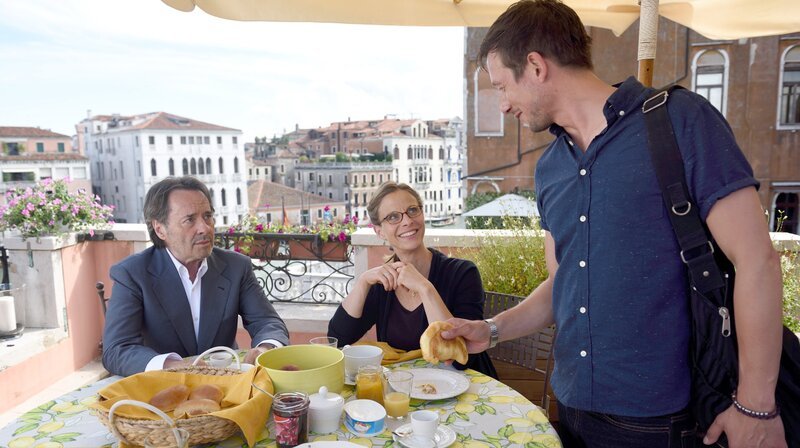 Brunetti (Uwe Kockisch, li.) und seine Frau Paola (Julia Jäger, mi.) sind froh, dass es Raffi (Patrick Diemling, re.) wieder gut geht. – Bild: ARD Degeto/​Nicolas Maas