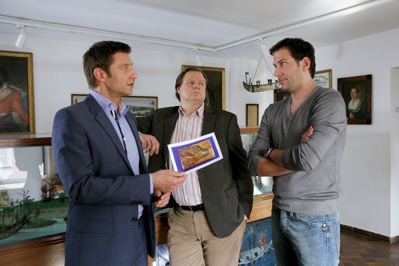 Für einen weiteren Schritt auf der Karriereleiter trauen Hartl (Michael A. Grimm, M.) und Hansen (Igor Jeftic, l.) Museumsmitarbeiter Christian Mendel (Ole Eisfeld, r.) sogar einen Mord zu. – Bild: ZDF/​Christian A. Rieger – klick