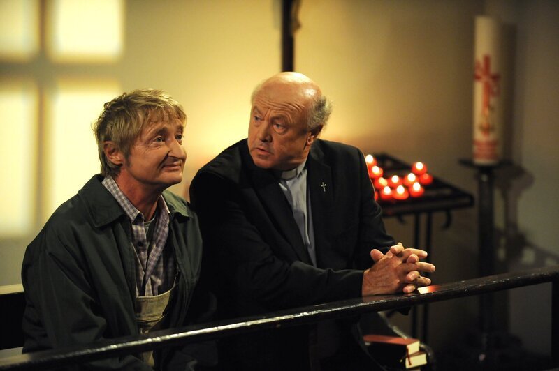 Pfarrer Kurz erzählt Xaver, wie ihm das Gebet zu den Schutzheiligen geholfen hat. Von links: Xaver (Michael Schreiner) und Pfarrer Kurz (Hans Stadlbauer). – Bild: BR/​Marco Orlando Pichler