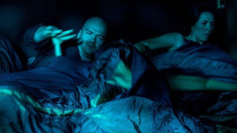 Ein Mann und eine Frau wachen mitten in der Nacht durch ein seltsames Licht auf – Bild: Warner Bros. Discovery