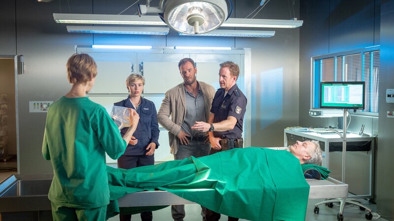 Helene (Katharina Blaschke, l.) freut sich über ungewöhnlichen Besuch in ihren Gefilden. Wenn Reuter unpässlich ist, müssen eben Lars Pöhlmann (Dominic Boeer, M.), Timmermann (Mathias Junge, 2.v.r.) und Stine (Sidsel Hindhede, 2.v.l.) ran. Wie sich herausstellt, ist Steffen Reinhard (Michael Kaune, liegend) mit Bleiacetat vergiftet worden. Aber wer wollte dem Unternehmer an den Kragen? – Bild: ZDF /​ Meyerbroeker