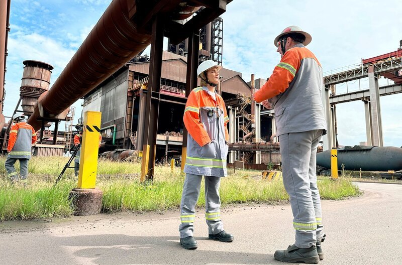 Die Stahlindustrie, hier das Werk von ArcelorMittal in Bremen, will ihre Produktion auf grünen Stahl umstellen. ARD-Wissen Presenterin Lena Ganschow besucht das Werk. – Bild: SWR/​BR/​EWE/​Nadine Auras