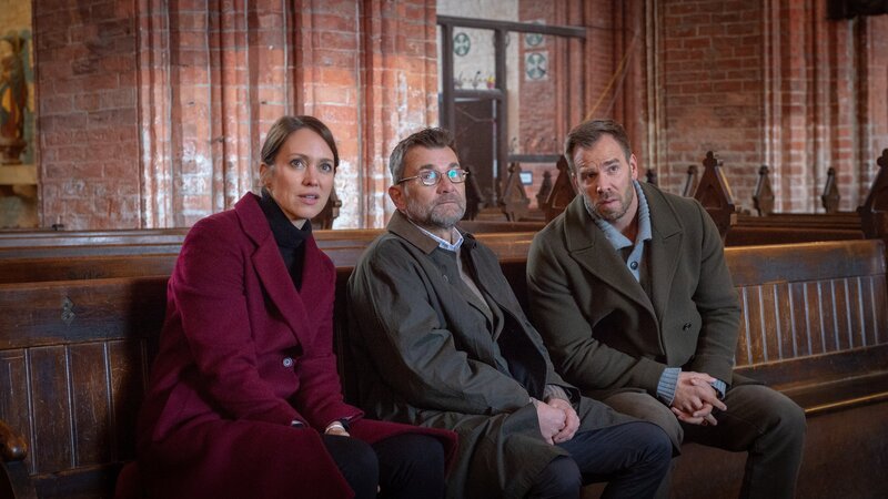 Gemeindekirchenrat Jan Sitten (Matthias Freihof, 2.v.l.) ist schwer getroffen vom Tod seines Freundes Sören Pielham (Stefan Witt). Die Kommissare Joost (Nike Fuhrmann, l.) und Pöhlmann (Dominic Boeer, r.) ermitteln, ob der Tote vor Kurzem Streit hatte und wer ein Motiv gehabt haben könnte. – Bild: Marc Meyerbröker /​ ZDF