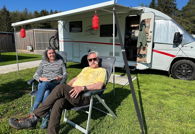 Petra (l.) und Rüdiger (r.) Erbslöh vor ihrem Wohnmobil auf dem Campingplatz River Camping Bled direkt am Bleder See. – Bild: WDR/​sagamedia GmbH