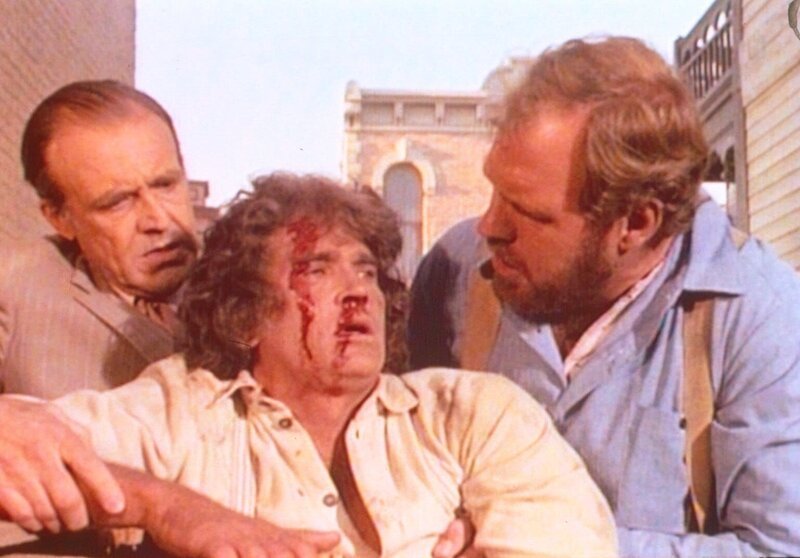 Charles (Michael Landon, M.) wurde niedergeschlagen. Jonathan (Merlin Olsen, r.) und Mr. Oleson (Richard Bull, l.) helfen ihm wieder auf die Beine. – Bild: Sat.1 Gold