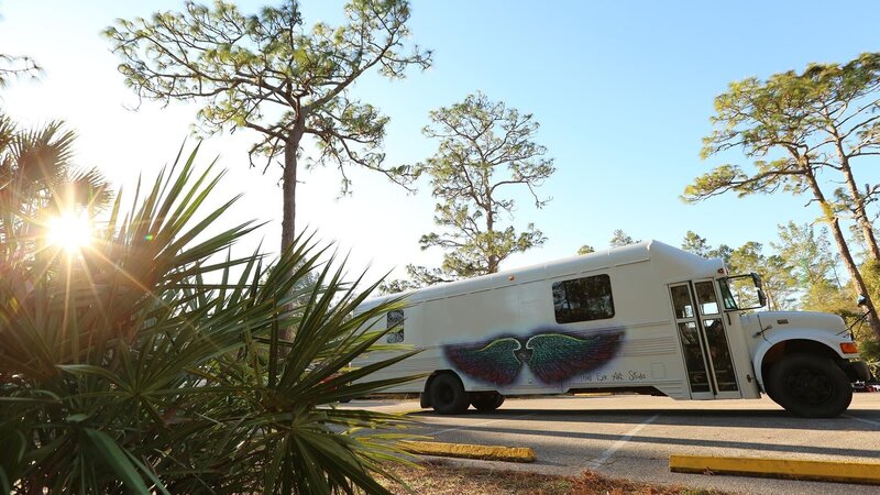 The setting sun peeks through a palmetto plant with a burst of light, with Kyle and Christiana Hill’s tiny house bus in the background, awaiting it’s first adventure, in Odessa, Florida, as seen on Tiny House, Big Living. – Bild: Scripps Networks, LLC