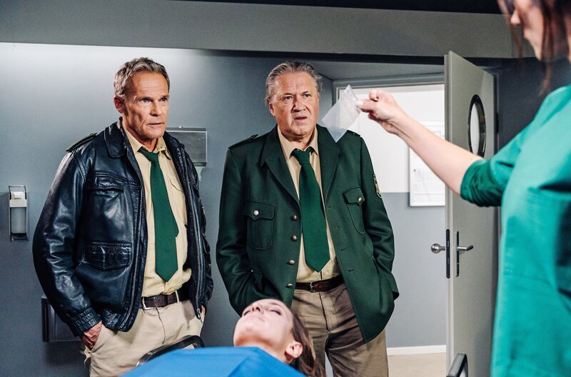 Dr. Fuchs (Susu Padotzke, r.) hat ein fremdes Haar im Auto der toten Frau entdeckt. Hubert (Christian Tramitz, l.) und Girwidz (Michael Brandner, 2.v.r.) müssen herausfinden, vom wem es stammen könnte. – Bild: ARD/​Max Bublak