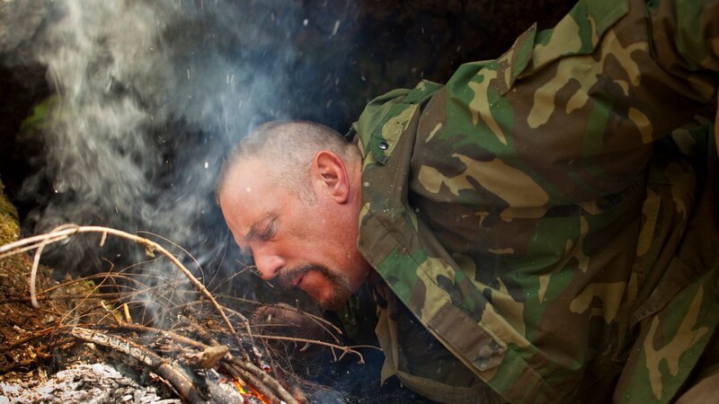 USA, Washington, Olympic National Forest, Dave Canterbury blows on campfire while camping in Pacific Northwest rainforest during Dual Survivor filming – Bild: Paul Souders /​ Discovery Communications