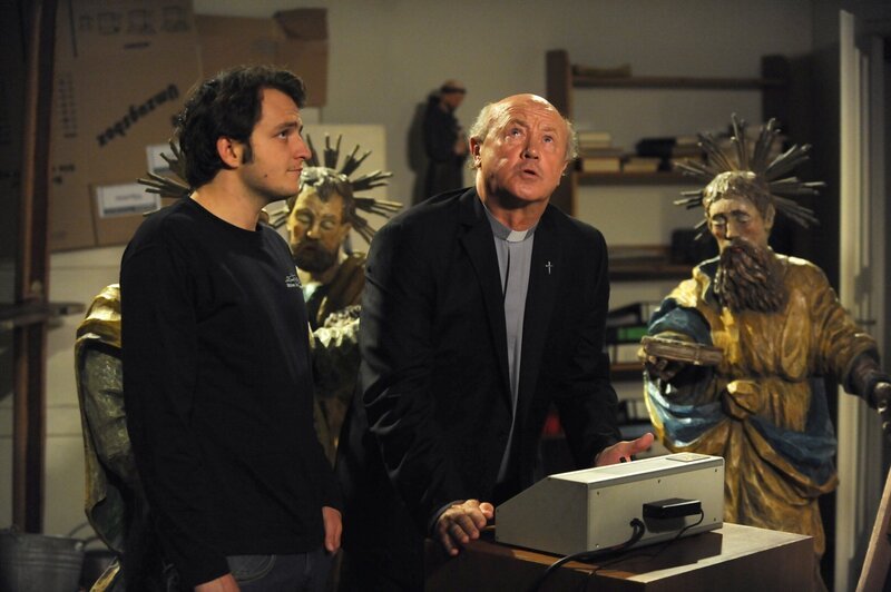 Der Pfarrer bittet um himmlischen Beistand, damit die Kirchenglocken wieder läuten. Von links: Florian Brunner (Tommy Schwimmer) und Pfarrer Kurz (Hans Stadlbauer). – Bild: BR/​Marco Orlando Pichler