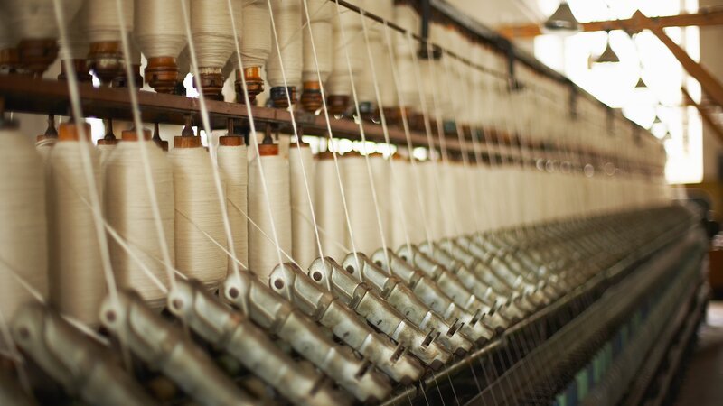 Spools of thread on machinery in textile mill. – Bild: Jupiterimages