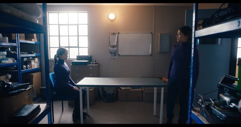 Zweimal Charlotte (Frances Mayli McCann) in der Abstellkammer. Die Charlotte, die am Tisch sitzt, ist ein Alien, das die Gestalt ändern kann. Es kann das Aussehen von jeder Person im Fabrikgebäude einnehmen. – Bild: ZDF und Zodiak Kids & Family Productions UK Ltd