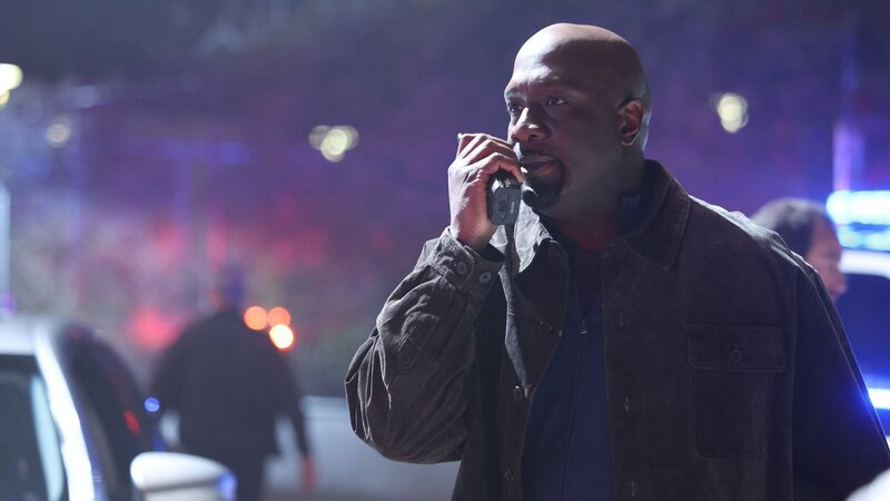 Officer Grey (Richard T. Jones) fordert über sein Funkgerät am Einsatzort Verstärkung an. – Bild: ZDFneo