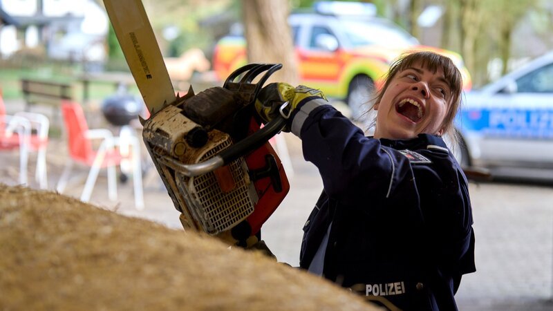 Jenny Dickel (Eva Bühnen) versucht den Toten mit einer Kettensäge aus dem Strohballen zu befreien. – Bild: WDR Mediagroup GmbH