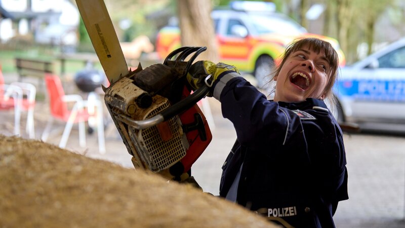 Jenny Dickel (Eva Bühnen) versucht den Toten mit einer Kettensäge aus dem Strohballen zu befreien. – Bild: WDR Mediagroup GmbH