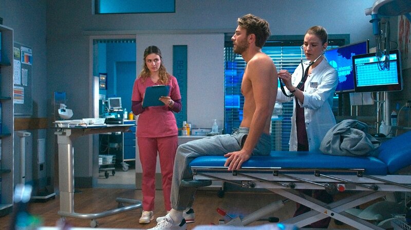 Dr. Julia Berger (Mirka Pigulla, r.) untersucht gemeinsam mit Viktoria Stadler (Isabella Krieger, l.) Luca Brendel (Frederik Götz, M.). Er leidet unter unerklärlichen Bauchschmerzen. – Bild: ARD/​Saxonia Media