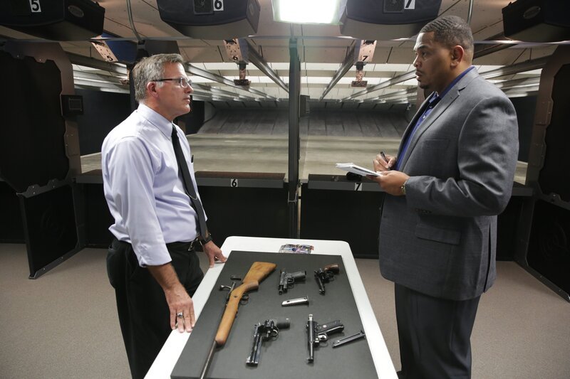 Chris Anderson and Professor Timothy Gossett converse over a table with guns laid out on it. – Bild: Discovery Communications