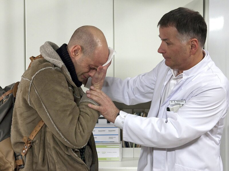 Schwester Yvonnes Bruder Paul Habermann (Benjamin Morik, links) taucht unerwartet in der Sachsenklinik auf. Dr. Roland Heilmann (Thomas Rühmann) findet ihn verletzt im Schwesternzimmer. – Bild: MDR/​Peter Krajewsky
