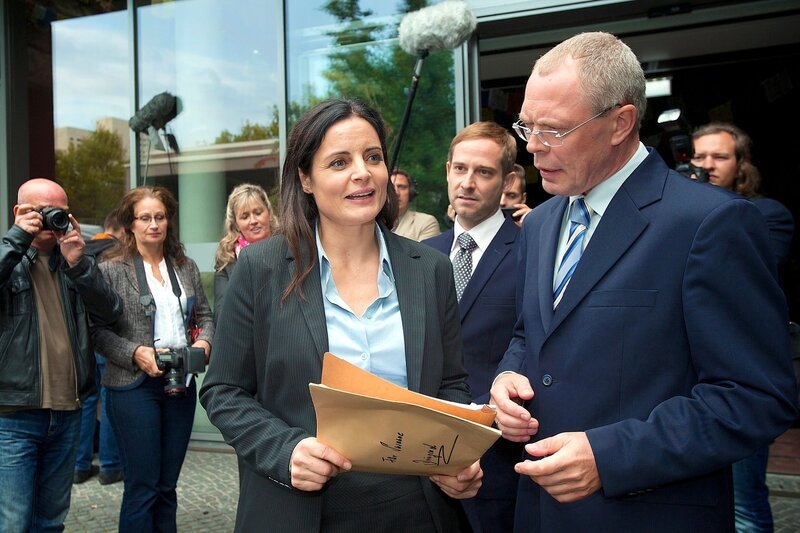Dr. Susanne Mertens (Elisabeth Lanz, links) konfrontiert OB Herrenbrück (Frank Siekel, rechts) mit einer Unterschrift als Beweis, dass sie Opfer einer Intrige von Dr. Bernd Schröder (Nils Bruno Schmidt, Mitte) wurde. – Bild: Bernd Cramer