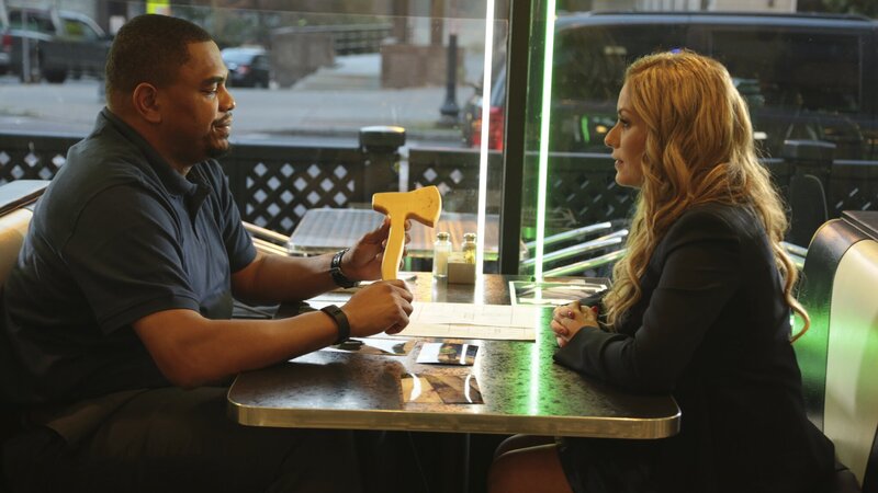 Melissa Lewkowicz sits across from Chris Anderson, hands folded. Chris Anderson is holding a wooden tomahawk. – Bild: TLC