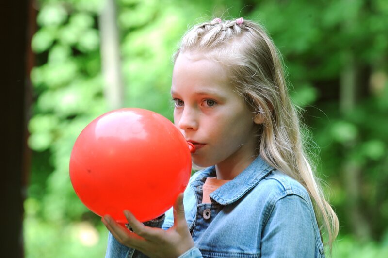 Franzi (Mia Löffler, KLD) zieht an einem mit Lachgas gefüllten Ballon. – Bild: Marco Orlando Pichler /​ BR