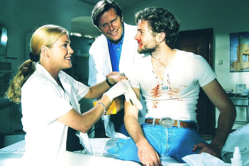 Ben (Peter Ketnath, re.) wurde von seinem Arbeitgeber zusammengeschlagen. Dr. Stefan Frank (Sigmar Solbach) und Laura (Cecilia Kunz) verarzten ihn. – Bild: RTLplus /​ Elke Werner