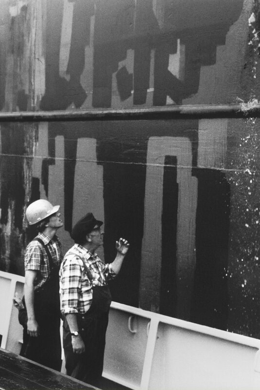 Wütend schauen Petermann (Uwe Dallmeier, rechts) und Harald (Marco Krüger) zum Frachter hinauf. Aus dessen Abflussrohr strömt üble Brühe aufs Deck der „Henriette II“. – Bild: NDR/​Stroemer