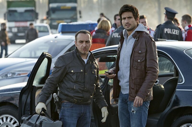 Semir (Erdogan Atalay, li.) und Ben (Tom Beck) haben die flüchtenden Männer nicht erwischt, doch im Kofferaum ihres Wagens entdecken die Kommissare eine Sporttasche voller Bargeld. – Bild: RTL /​ Guido Engels